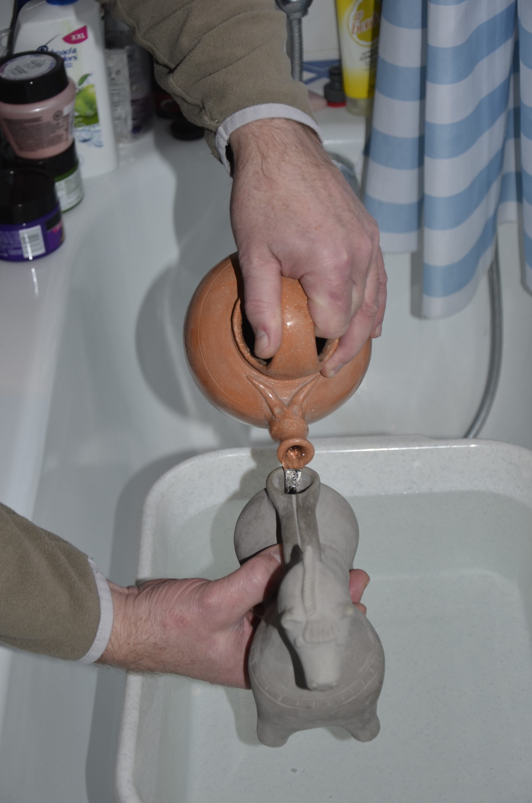 Abb. 12: Befüllen des Keramik-Aquamanile mit der Bügelkanne durch eine Person. Foto: Thomas Kühtreiber.