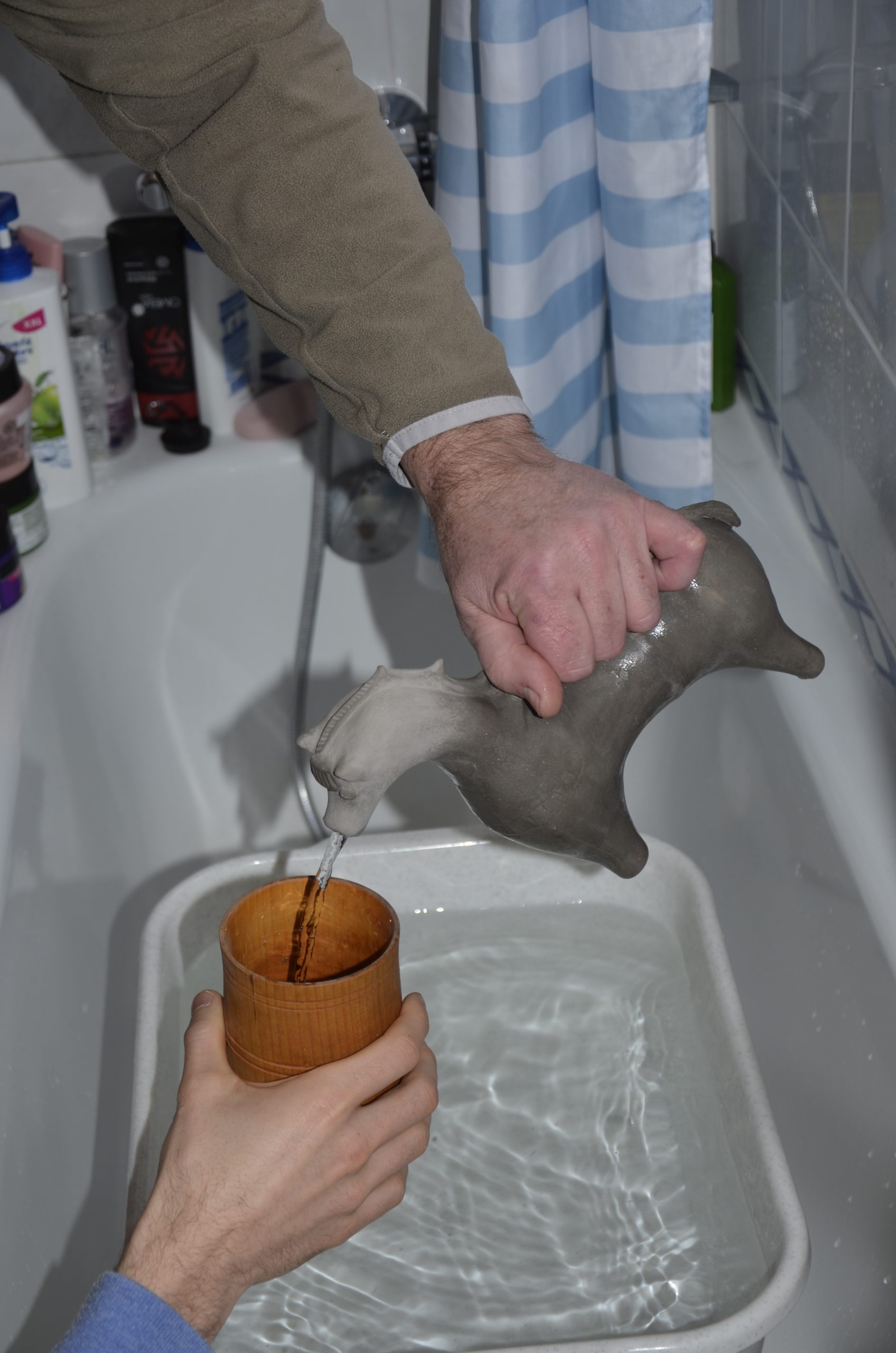 Abb. 16: Befüllen eines Bechers mittels des Keramik-Aquamanile durch eine Person. Foto: Thomas Kühtreiber.